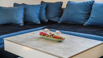 Un salon moderne avec un canapé d’angle, une petite table agrémentée d’un élément décoratif central et une vue sur l’extérieur.