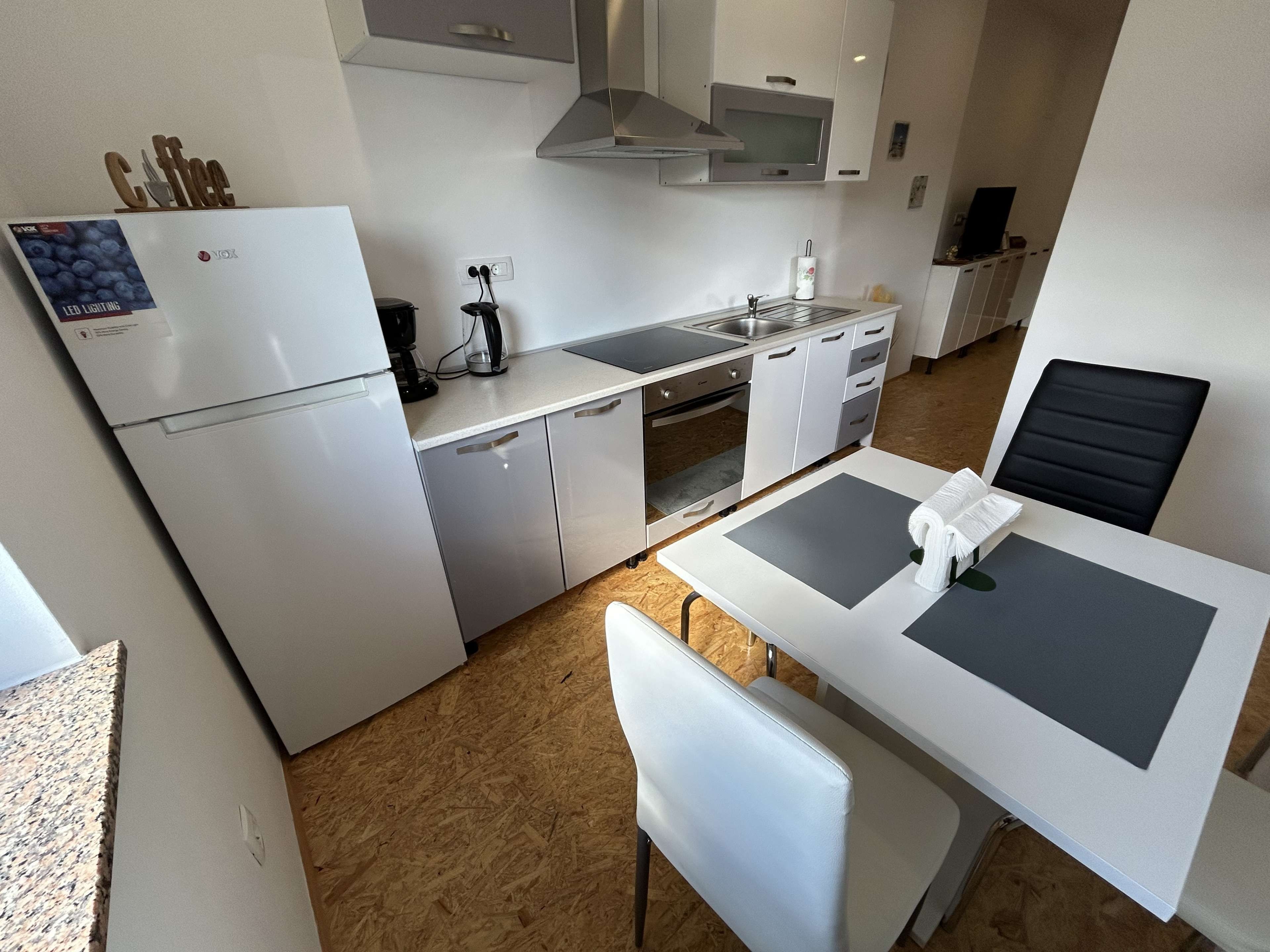 Une cuisine compacte équipée d’un réfrigérateur, d’une cuisinière, d’un four à micro-ondes et d’un coin repas avec une table et des chaises.