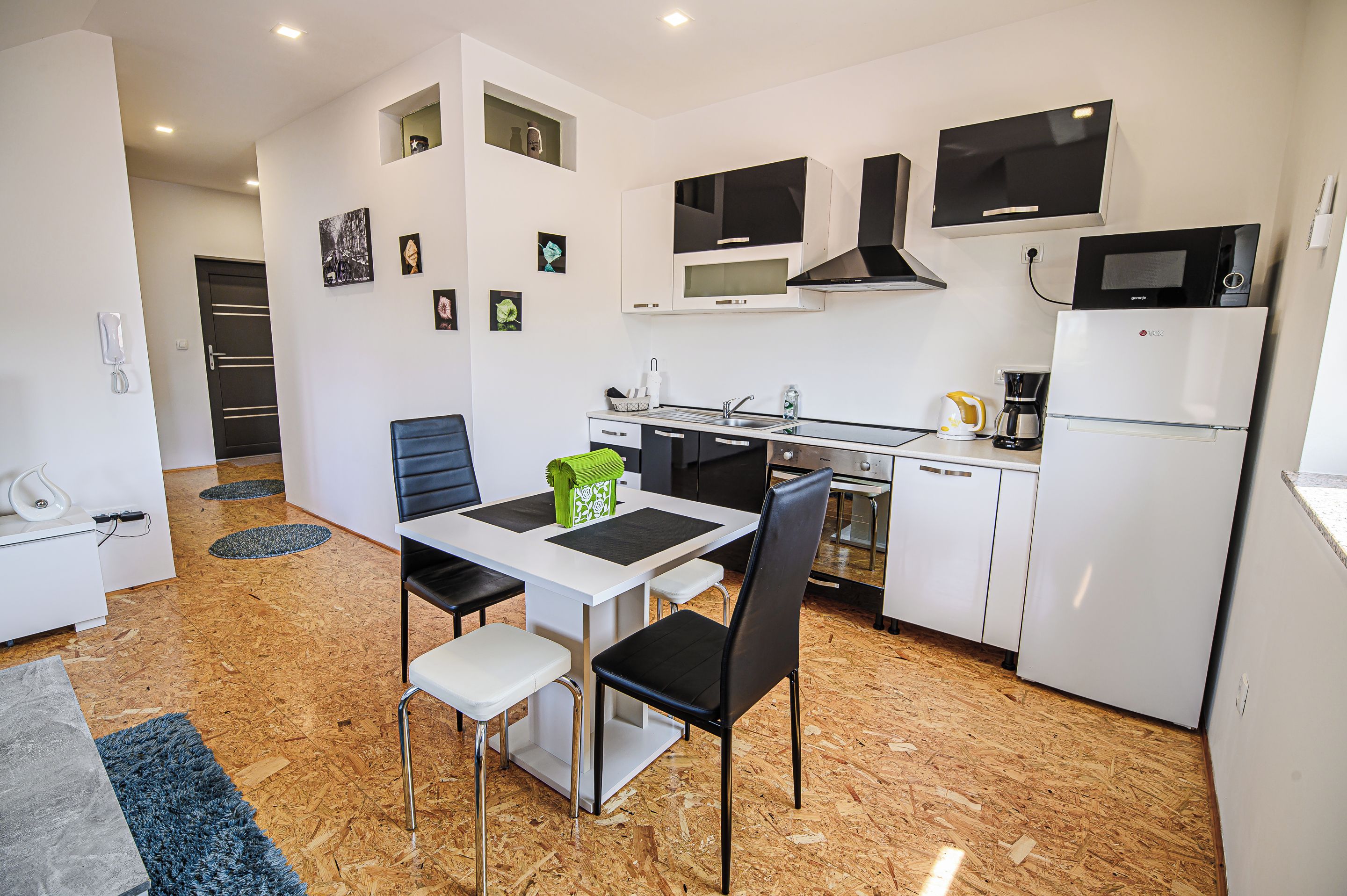 A modern kitchen with white cabinetry, a dining table with chairs, and a microwave above the stove.