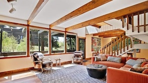 A spacious living area with large windows, a wooden staircase, and a cozy seating arrangement. - Mountain Chalet Just Blocks from Gondola & Main St (Breckenridge)