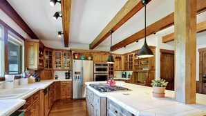 A kitchen with wooden cabinets, a large island with a stove, and pendant lighting. - Mountain Chalet Just Blocks from Gondola & Main St (Breckenridge)