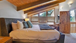 A bedroom with a large bed, wooden ceiling beams, a window with a view, and a door to the outside. - Mountain Chalet Just Blocks from Gondola & Main St (Breckenridge)