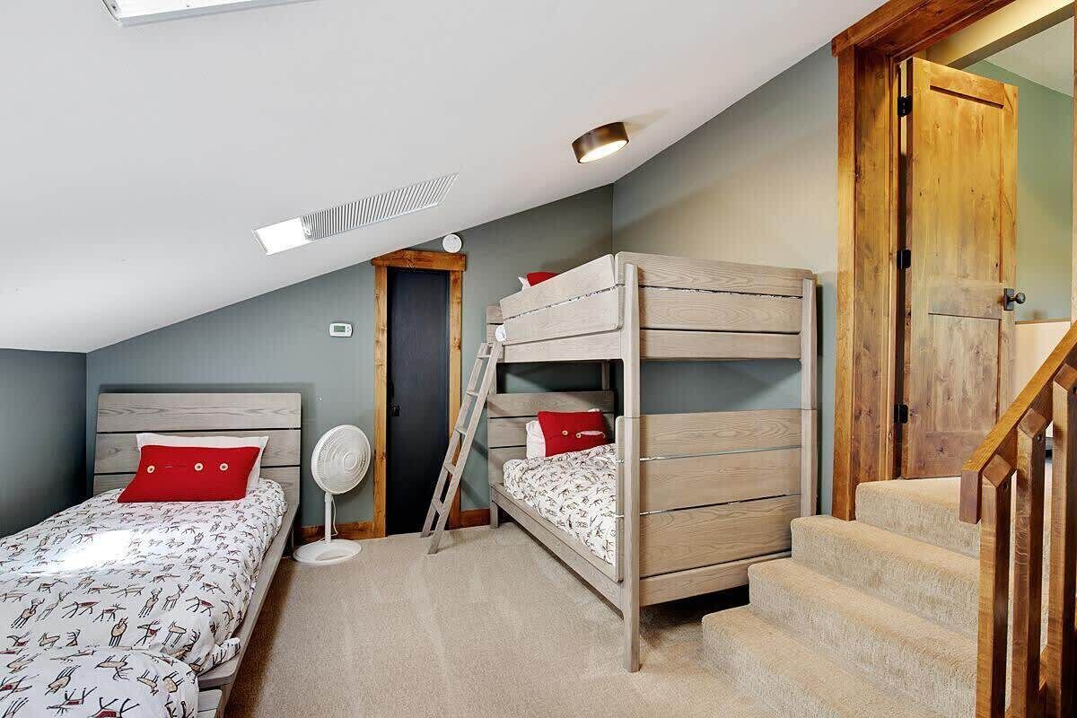 A bedroom with bunk beds, a ladder, a fan, and a staircase.