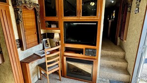 A cozy living room with a fireplace, wooden cabinets, a TV, and a comfortable seating area.