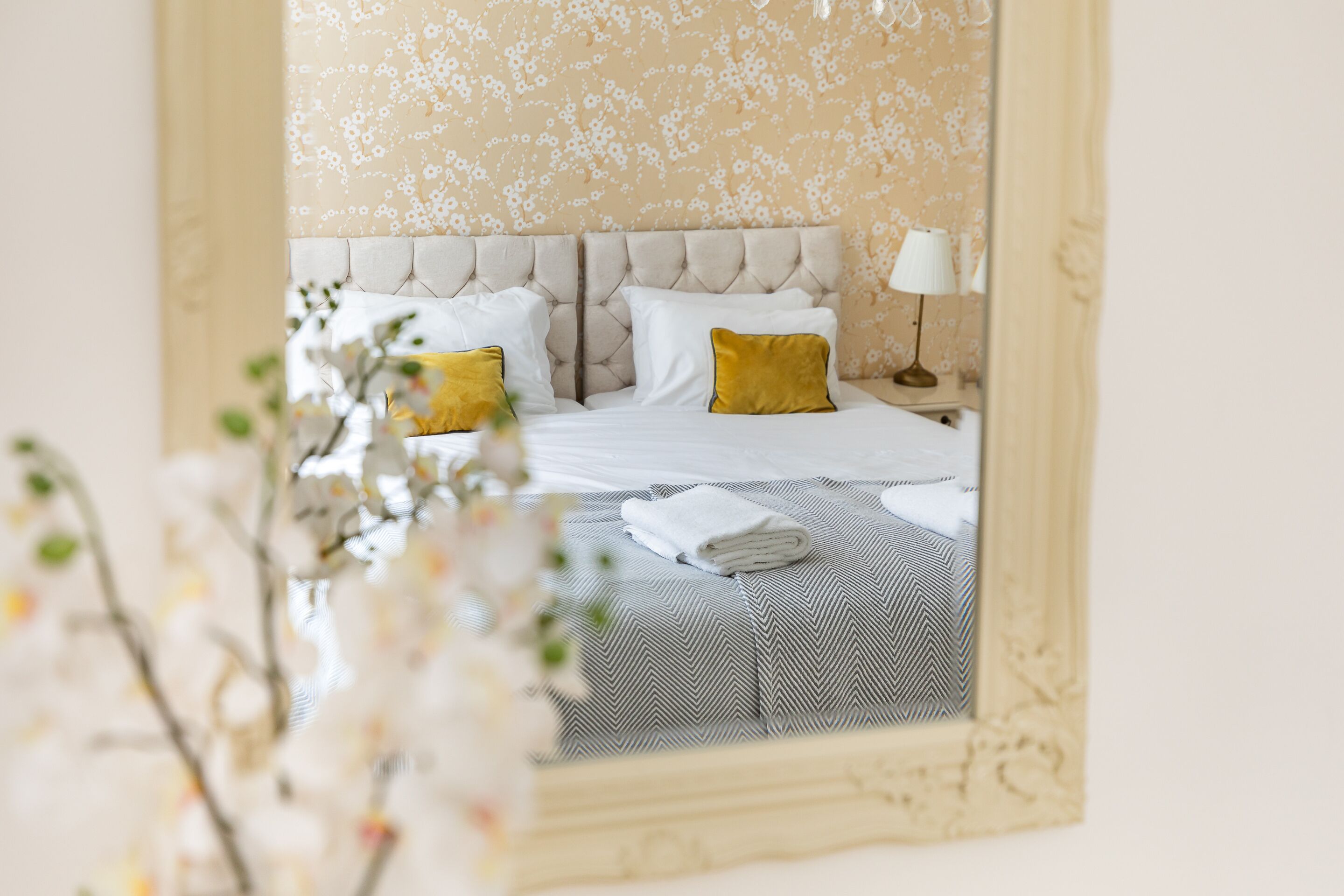 Une chambre d’hôtel avec un lit, des oreillers, une lampe et un miroir.