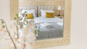 Une chambre d’hôtel avec un lit, des oreillers, une lampe et un miroir.