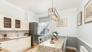 Une cuisine moderne avec des meubles blancs, un réfrigérateur en acier inoxydable et un coin repas avec une table dressée pour deux personnes.