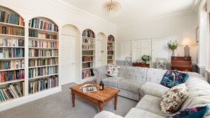 Un salon spacieux avec un grand canapé d’angle, une table basse en bois et de nombreuses étagères remplies de livres.