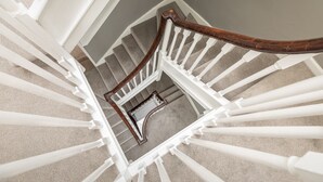 Un escalier en colimaçon avec des rampes blanches et une main courante en bois.