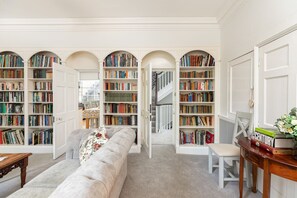 A library with bookshelves, a sofa, and a staircase.
