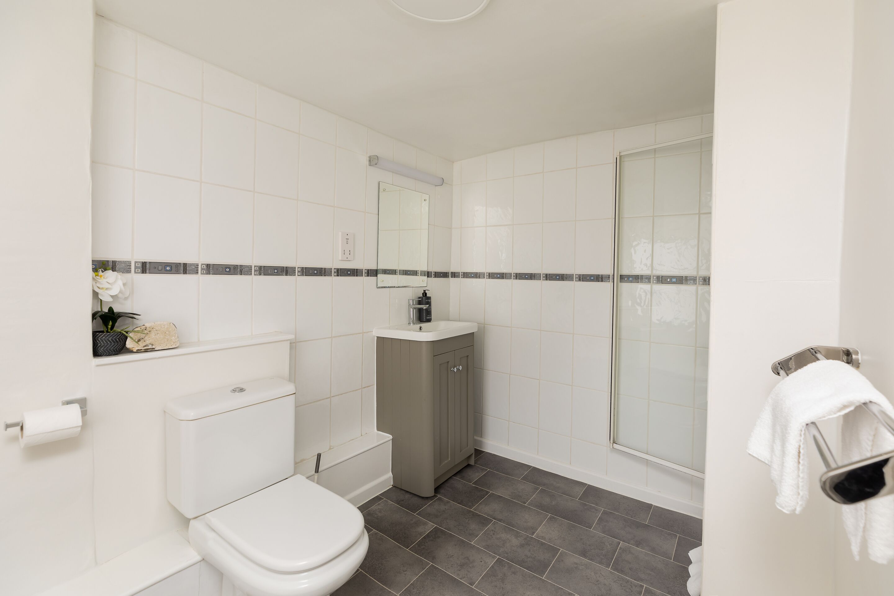 Een badkamer met toilet, wastafel, spiegel en douche.