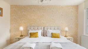Un lit bien fait, avec deux oreillers, deux lampes de chevet et une serviette pliée posée sur le lit.