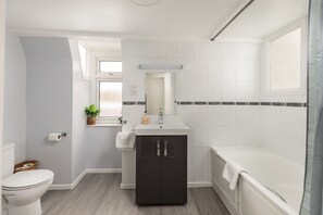 Une salle de bain comprenant des toilettes, un lavabo, un meuble et une baignoire.