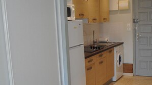 Een kleine keuken met een koelkast, magnetron, fornuis, spoelbak en wasmachine.