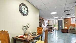 Un comedor con una mesa de madera, sillas y un reloj en la pared.