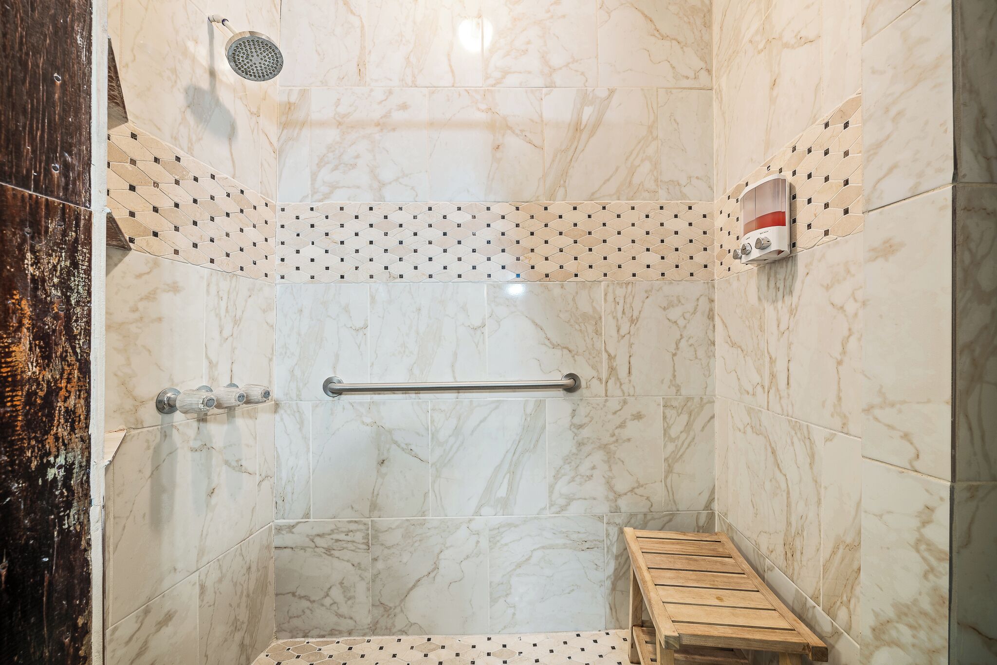 A shower with a handheld showerhead, a handheld showerhead, and a handheld showerhead.