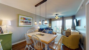 A dining area with a wooden table and chairs, a sofa, and a television. - April's Retreat - Oceanfront! Special rates for July 4-11! (Atlantic Beach)