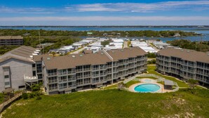 A modern hotel with multiple floors, a central courtyard with a swimming pool, and a view of the water body in the background. - April's Retreat - Oceanfront! Special rates for July 4-11! (Atlantic Beach)