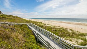 A coastal walkway leading to a beach with a clear view of the ocean.