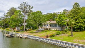 A waterfront property with a dock, a house with a porch, and lush greenery.