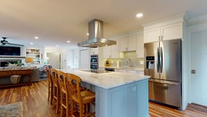 A modern kitchen with a central island, stainless steel appliances, and wooden chairs.
