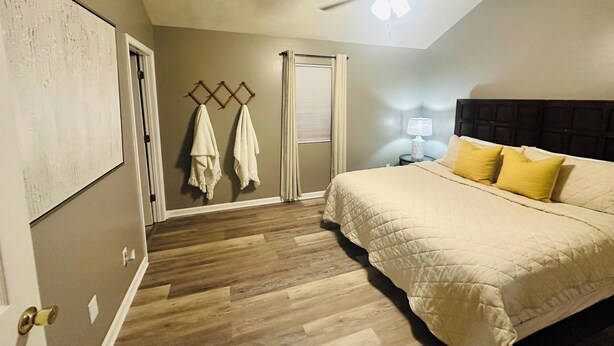 Un dormitorio con cama, ventilador de techo, mesita de noche y puerta que da a otra habitación.