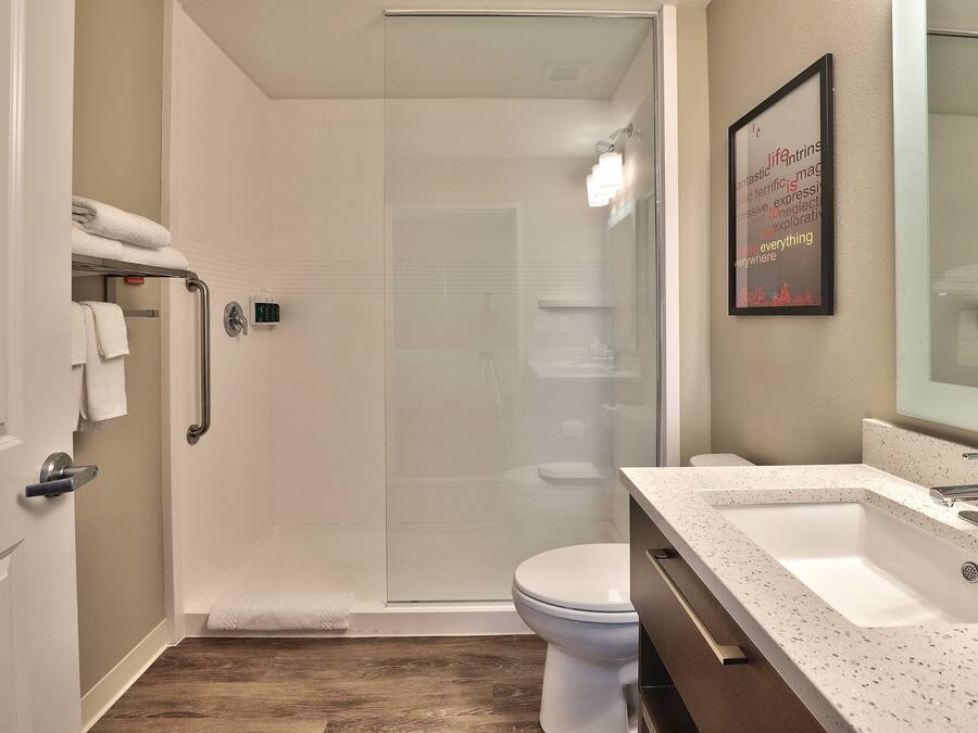 A modern bathroom with a glass shower enclosure, a white toilet, and a sink with a speckled countertop.