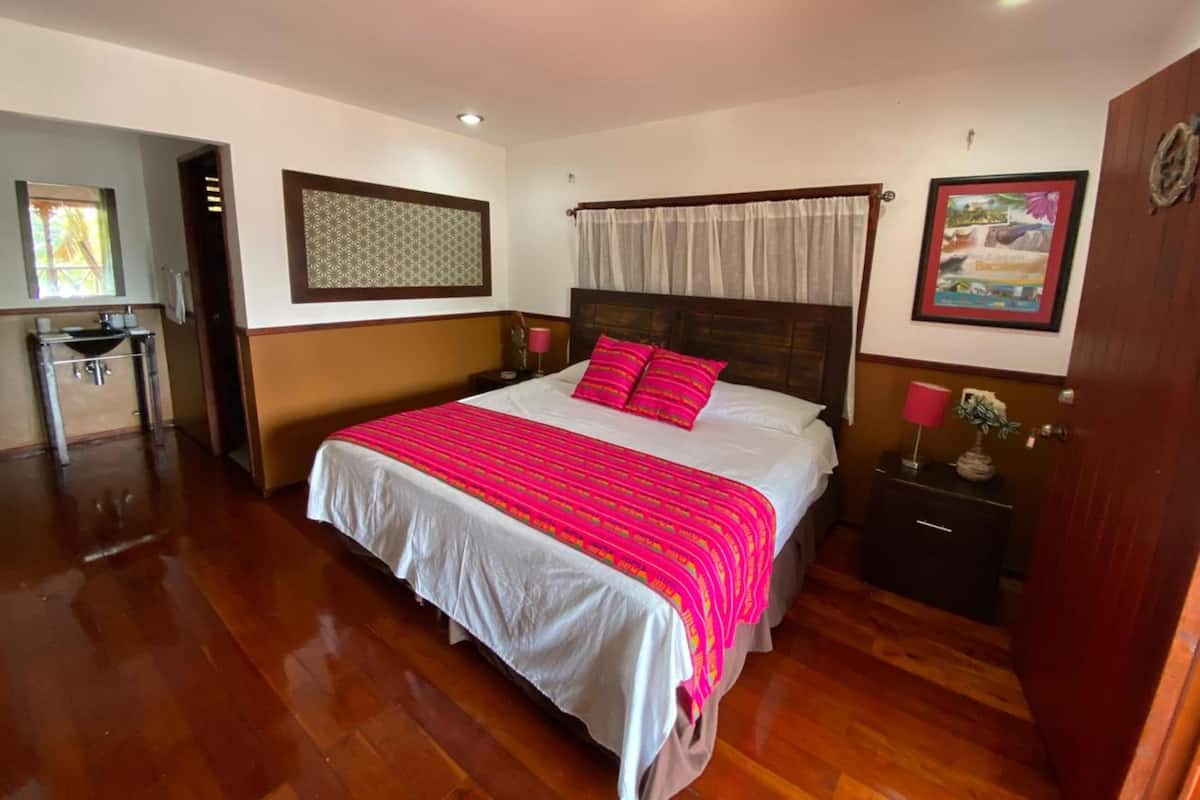 Une chambre à coucher avec un grand lit, une table de chevet, une commode, une fenêtre et une porte.