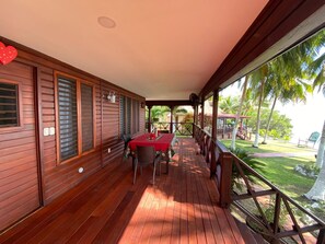 Una terraza de madera con una mesa y sillas, con vistas a un jardín tropical con palmeras.