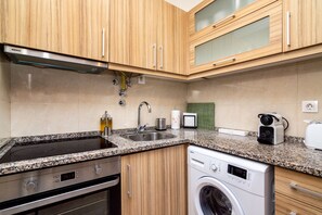 Equipped with a stainless steel range hood, dishwasher, and double sink, this kitchen offers a convenient cooking space.