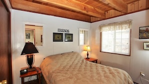 A bedroom with a large bed, two bedside lamps, a mirror, and a window with blinds. - Cozy Cabin, Views, Walk to Bear Mountain Resort (Big Bear Lake)