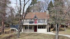 A two-story building with a balcony, a red door, and a stone chimney. - Cozy Cabin, Views, Walk to Bear Mountain Resort (Big Bear Lake)