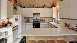 A modern kitchen with white cabinets, a central island, and wooden flooring. - Cozy Cabin, Views, Walk to Bear Mountain Resort (Big Bear Lake)
