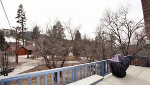 A wooden deck with a blue railing, a covered object, and a garage in the background. - Cozy Cabin, Views, Walk to Bear Mountain Resort (Big Bear Lake)