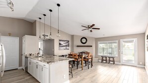 A spacious kitchen with a large island, wooden flooring, and a dining area with chairs and a table. - The Diamond - Private Pool / Pet Friendly / 4BD Near Arena (Phoenix)