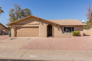 A single-story house with a garage, a brick facade, and a clear blue sky.