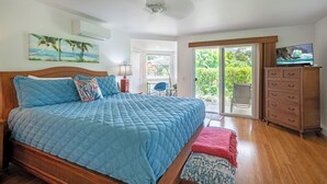A bedroom with a large bed, a TV, a dresser, and a balcony with a view. - Elegant Air-Conditioned Villa by Golf Course - Near Beaches, Shopping, Dining (Princeville)