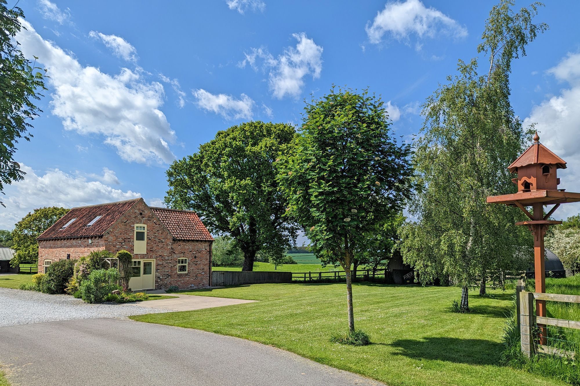 A brick building with a sloped roof, a small garden area, and a wooden fence.