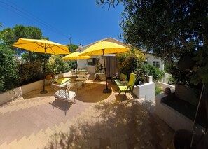 Une terrasse extérieure avec des parasols jaunes, des meubles en osier et des plantes en pot.