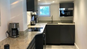 Cozinha moderna com ilha central, eletrodomésticos embutidos e iluminação pendente.