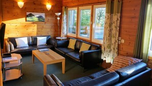A cozy cabin interior with a sofa set, a coffee table, and a TV stand.