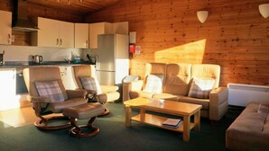Un intérieur de chalet chaleureux comprenant une cuisine, deux canapés, une table basse et une table à manger.
