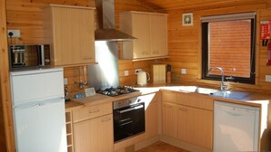 A compact kitchen with wooden cabinets, a microwave, a stove, and a sink.
