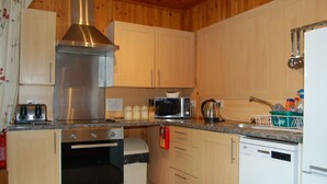 Kompakti keittiö, jossa on puukalusteet, ruostumattomasta teräksestä valmistettu liesituuletin, mikroaaltouuni, leivänpaahdin ja astianpesukone.