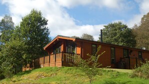 Eine Holzhütte mit Balkon, umgeben von Bäumen und Gras.
