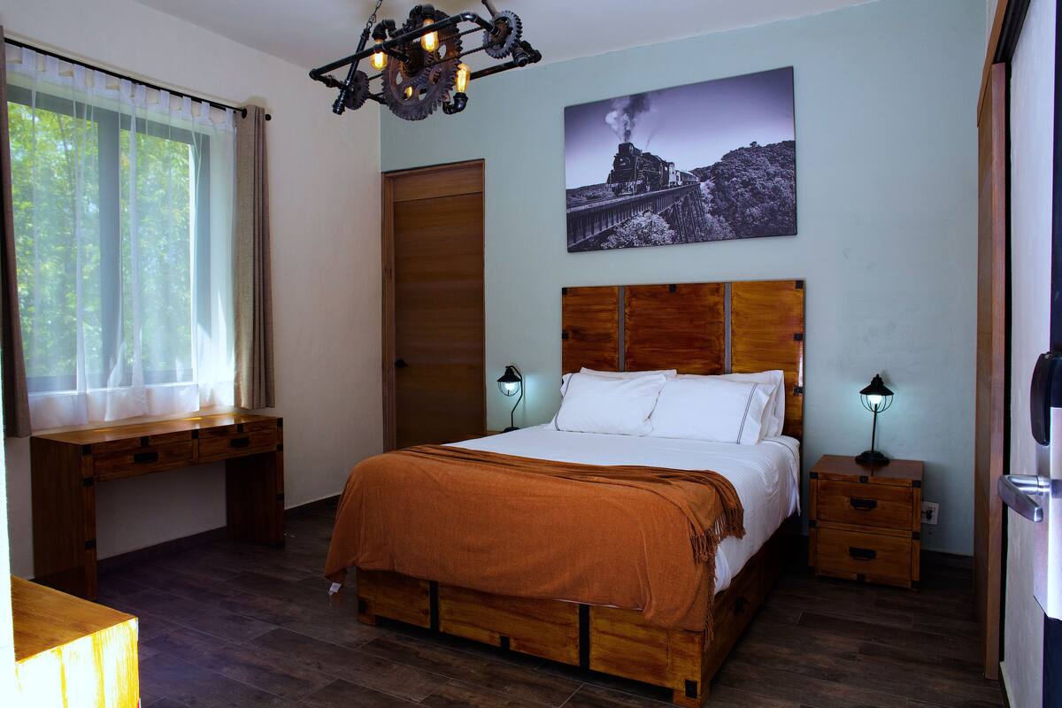 A bedroom with a wooden bed, a desk, and a nightstand.