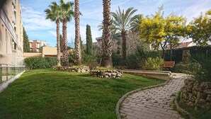 Ein gepflegter Innenhof mit Pflasterweg, Palmen und einer Steinmauer.