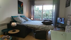 Ein Schlafzimmer mit einem Bett, einem Fernseher, einem Sessel, einem Tisch und einem Gemälde.