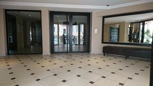 Eine großzügige Lobby mit Fliesenboden, einer Bank und Glastüren, die nach draußen führen.
