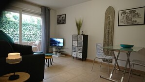 Ein Wohnzimmer mit Sofa, Fernseher, Schrank und Essbereich mit Tisch und Stühlen.
